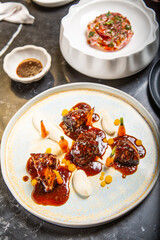 Chef decora un plato de carne a la parrilla con salsa glaseada en un plato con zanahorias salsa de...