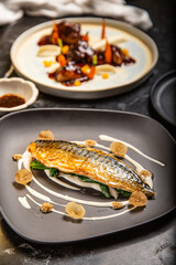 Pescado fresco con salsa con hierbas decorativas servido en un plato y decorado en una mesa de restaurante delicioso y muy jugoso