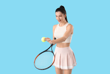 Sporty young woman playing tennis on blue background