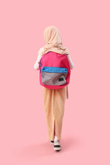 Little Muslim girl in hijab with school backpack on pink background, back view