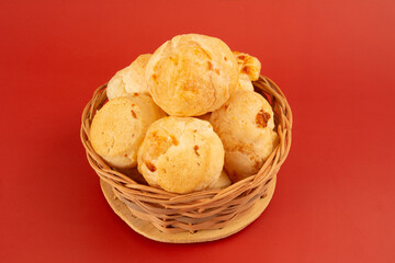 Brazilian cheese bread inside a wooden basket in a clean red background in front top view