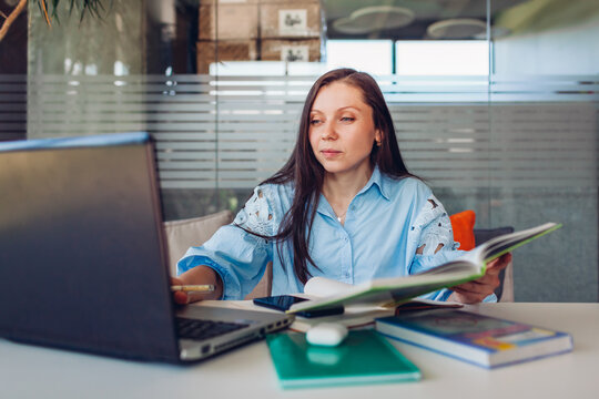 Young businesswoman working online in office using laptop. Middle-aged woman searching for information sitting at desk