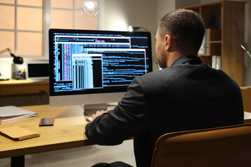 Programmer coding with computer on table in office at night