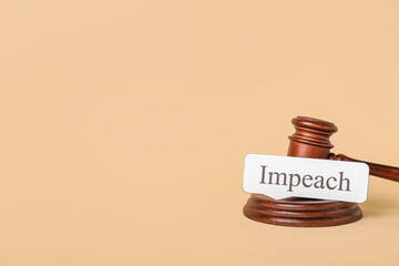 Judge gavel with word IMPEACH on beige background