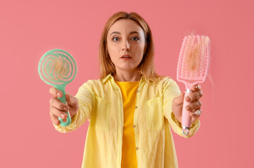 Worried mature woman with hair loss problem and brushes on pink background