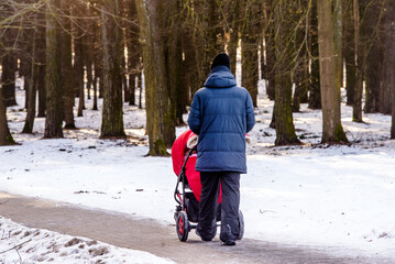 Fototapeta na wymiar men carries a child in a wheelchair in the winter Park 