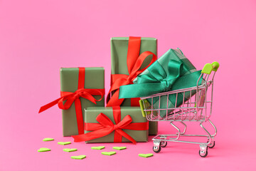 Small shopping cart with gift boxes on pink background. Valentine's Day celebration