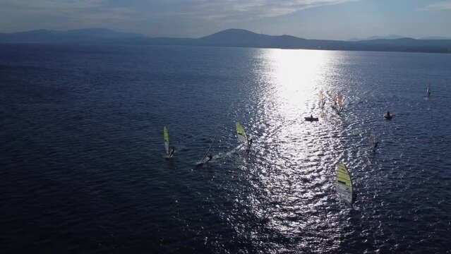 Windsurfers at the winter, aerial training footage 4k. This video made with a drone at sunset with a windsurfers on the board surfing at winter period in Loutsa, Greece
