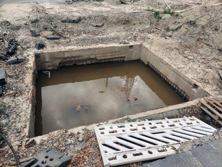 A square hole was dug on the road with sewage pipes flooded by water