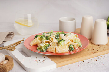 Plate of tasty pasta with broccoli on white background