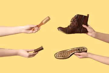Female hands with shoe pieces, brush and sewing thread on yellow background. Shoes repair concept