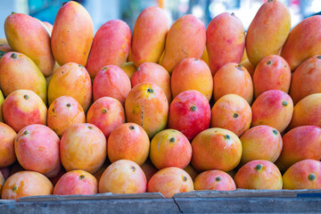 Display of Mangga Podang (Podang Mango variety) or Mangga Kenyot on a market stall. Originated from Kediri, East Java, Indonesia. Known for its vibrant red-orange skin, with sweet and juicy flesh.