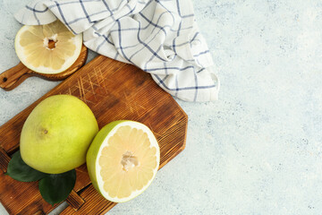 Wooden boards with fresh pomelo fruits and leaves on white background