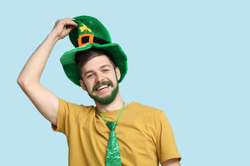Young man in leprechaun hat with green beard on blue background. St. Patrick's Day celebration