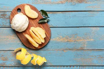 Board with fresh pomelo fruit and leaves on blue wooden background