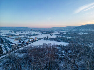Aerial image of wonderful, snow covered landscape of valleys and frozen forest around town of...