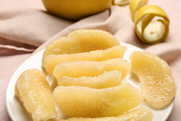Plate with pieces of fresh pomelo fruit on pink background
