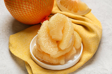 Plate with pieces of fresh pomelo fruit on white background