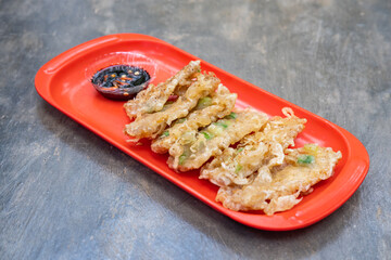 Fried tempeh or tempe goreng, a traditional Indonesian food made from fermented soybean. Served sambal (chili paste) on a red plate. 
