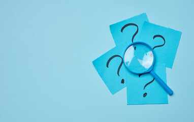 Drawn question marks on stickers and a magnifying glass, blue background.