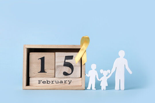 Family figurines with calendar and golden ribbon on blue background. Childhood cancer awareness concept