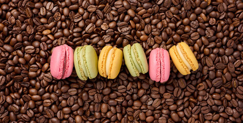 Multi-colored macarons on a background of coffee beans, top view