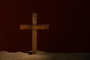 Wooden cross on sand against black background. Good Friday concept