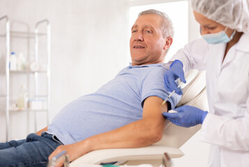 Retired man sitting at therapist appointment and undergoing procedure of mandatory annual...