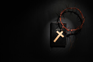 Wooden cross with crown of thorns, Bible and nails on black background. Good Friday concept
