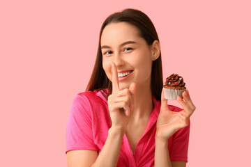 Young woman with sweet cupcake on pink background. Valentine's Day celebration