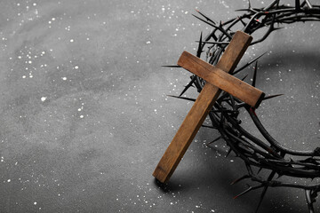 Wooden cross with crown of thorns on black grunge background. Good Friday concept