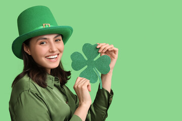 Beautiful young woman in leprechaun hat with clover on green background. St. Patrick's Day...