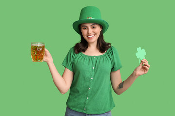 Happy young woman in leprechaun hat with glass of beer and clover on green background. St....