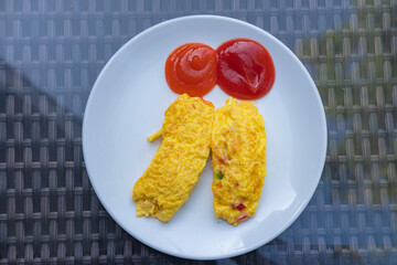 Classic omelet served on a white plate with tomato and hot sauce.