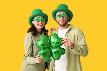 Beautiful young couple in leprechaun hats and decorative glasses with air balloon in shape of...