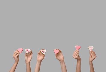 Women with heart-shaped cookies on grey background. Valentine's Day celebration