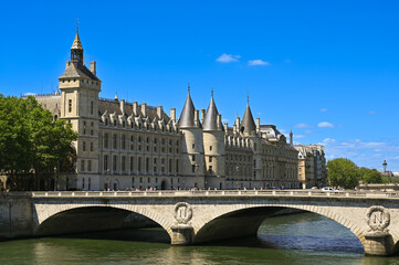 Fototapeta na wymiar Nice shot of the Conciergerie Castle and the Bridge of Change (Pont au Change) over the Seine. Passage of pedestrians and cars on the bridge, beautiful summer day.