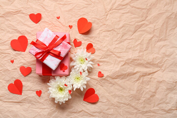 Gift boxes with white chrysanthemum flowers and hearts on crumpled paper. Valentine's Day celebration