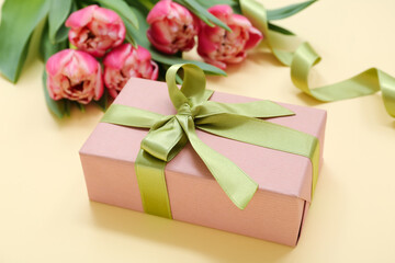 Gift box and bouquet of beautiful tulips on yellow background. International Women's Day