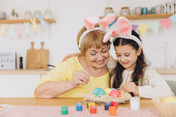 Obraz na płótnie Canvas Happy easter! A grandmother and her granddaughter painting Easter eggs