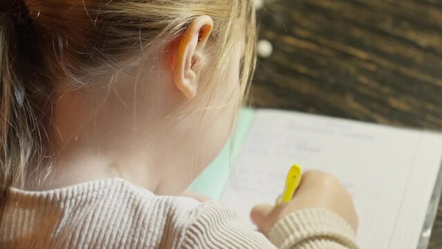 Girl studying at home. Pupil doing math homework. Children education concept. Preparation for school. School girl writing in exercise book doing homework. Close-up in 4K, UHD