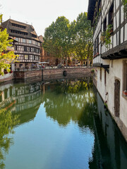 Fototapeta na wymiar Charming historical half-timbered buildings on the canal in the heart of Strasbourg, France. The canal reflect the scene. A UNESCO World Heritage Site.