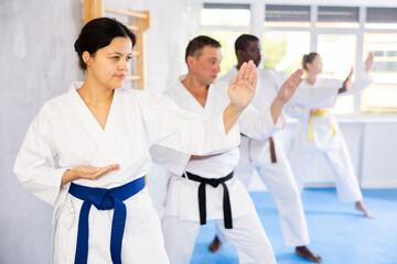 Fototapeta na wymiar Group of multiethnic people in kimonos train karate techniques in studio