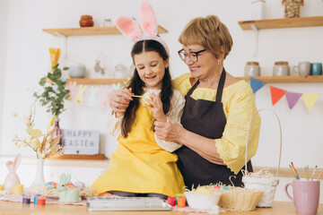 Happy easter! A grandmother and her granddaughter painting colorful eggs
