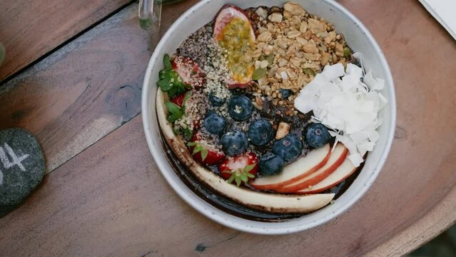 Top view of table setting, tasty healthy acai bowl with berries, passion fruit and granola. Beautiful breakfast. Superfood smoothie bowl 
