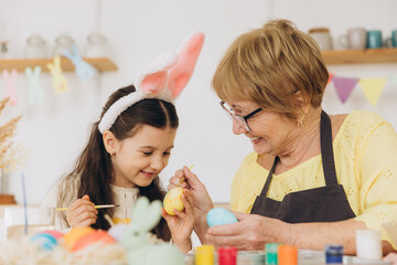 Happy easter! A grandmother and her granddaughter painting colorful eggs