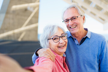 Personal perspective of a happy elder couple taking a selfie in an urban modern space