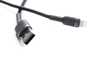 Black USB braided cable - Lightning isolated on a white background, close -up. (selective focus)