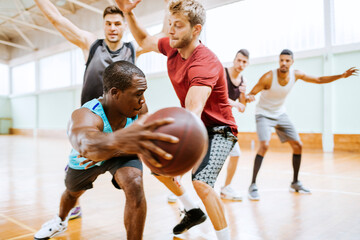 Diverse group of young men playing basketball in an indoor basketball gym