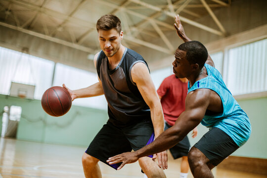 Basketball players playing basketball in an indoor basketball gym